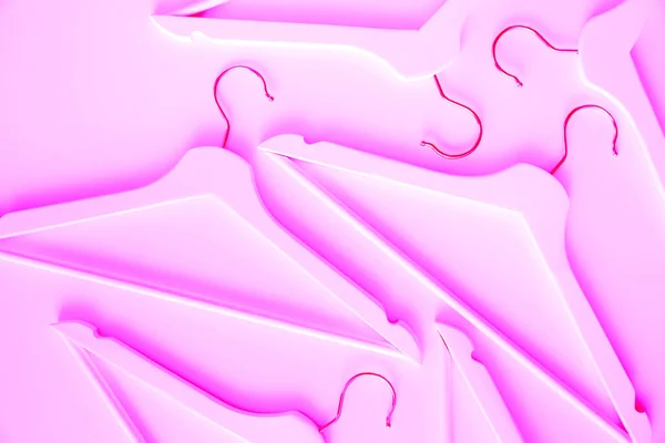 Neon purple wooden clothes hangers on a pink background. Modern shopping concept.