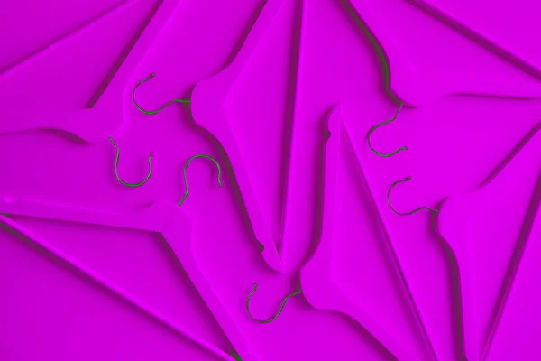 Neon wooden clothes hangers on a purple background. Sale and shopping concept. Modern fashion.