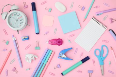 Pembe arka planda okul ve ofis malzemeleri, yakın planda üst görünüm.