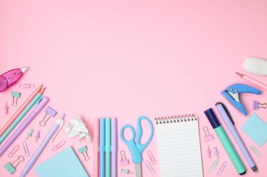 Pembe arka planda okul ve ofis malzemeleri, yakın planda üst görünüm.