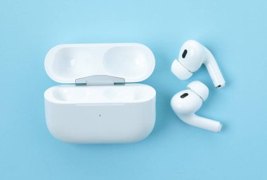 Kiev, Ukrayna - 10 Haziran 2023: Kulaklıklar Apple Air Pods Pro 2 mavi arka planda kablosuz şarj davası, üst manzara. AirPodlar Apple Inc. 'in tasarladığı kablosuz bluetooth kulaklıklardır..