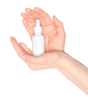 Beyaz bir kozmetik şişesi tutan kadın elleri, beyaz arka planda kapalı, kozmetik reklamları için şablon.