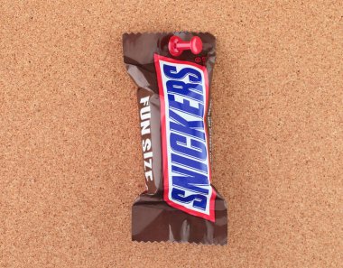 Pakette çikolatalı Snickers, mantar ağacına, yiyecek ve atıştırmalık konseptine tutturulmuş. Snickers, üzerinde karamel ve fıstık olan bir çikolatadır.