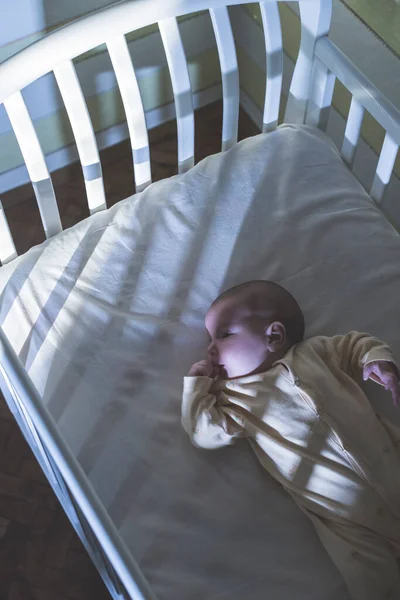 宝宝躺在床上晚上的婴儿房 免版税图库照片