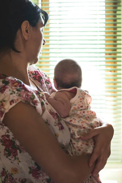 엄마와 아기를 창밖으로 꽃무늬 블라우스 스톡 사진