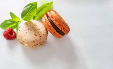 Böğürtlen dolgulu ve ahududulu iki badem kurabiyesi fotokopi alanı olan açık gri bir arka planda yatıyor. Fransız geleneksel kurabiyeleri