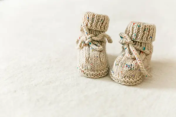 Örülmüş bebek çorapları, beyaz arka planda fotokopi alanı olan ayakkabılar. Hamilelik ve annelik konsepti, ilk doğum günü afişi, el yapımı çoraplar, bebek için sıcak kıyafetler, el yapımı çoraplar, hobi.