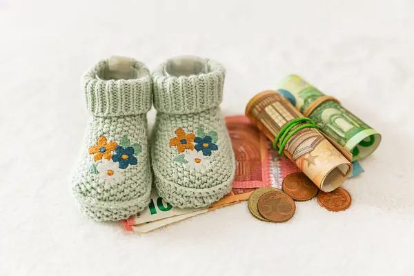 Çocuk çorabı ve para, beyaz bir arka planda para. Hamilelik ve annelik kavramı. Çocuk parasının ödenmesi, pahalı çocuk kıyafetleri, aile bütçesi, gider planlaması