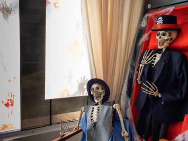 Cadılar Bayramı süslemeleri, ürkütücü temalar ve tatil gösterileri. Kostümlü iki insan iskeleti ürkütücü bir Cadılar Bayramı sahnesini resmediyor..