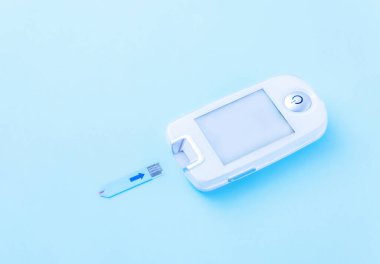 Diabetes mellitus. Close-up of a glucometer - a medical device for measuring blood glucose levels on a blue background with copy space. Self-monitoring of your health. Lifestyle, insulin dependence clipart