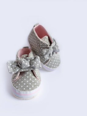 Yeni doğmuş bir kız için rahat ayakkabılar, beyaz arka planda fiyonklu gri kız çizmeleri, çocuk ayakları için rahat. Hayatının ilk yılı için doğru çocuk ayakkabısı seçimi..