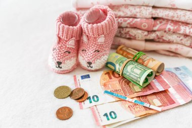 Hamilelik testi, para, euro, banknotlar ve kıyafetler, yeni doğan bebekler için eşyalar. Hamilelik planı, tüp bebek, çocuk için para, çocuk için devlet ödemeleri, sağlık sigortası.