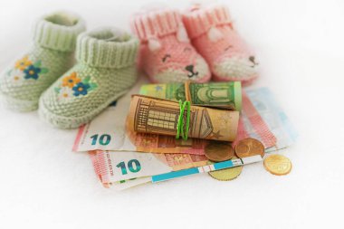 Para, hamilelik testi, beyaz arka planda bebek ayakkabıları, tüp bebek fiyatı, çoklu hamilelik planı, sağlık sigortası, düşük doğum oranı, nüfus sorunları.