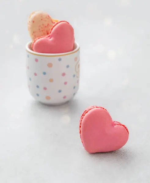 Romantik tatlı. Renkli kalp şeklinde makaronlar. Arka planda hafif bir fincanda Bokeh ile birlikte. Tatlılar ve tatil temaları için güzel bir kompozisyon. Sevgililer günü, anneler günü, tebrikler..