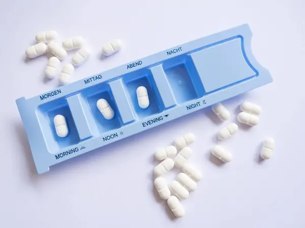 Plastik hap organizatörü, günün saatine göre sıralanmış tabletlerle. Sabah, öğleden sonra ve akşam. Uygun ilaç alımı, evde tedavi ve dozaj kontrolü kavramı