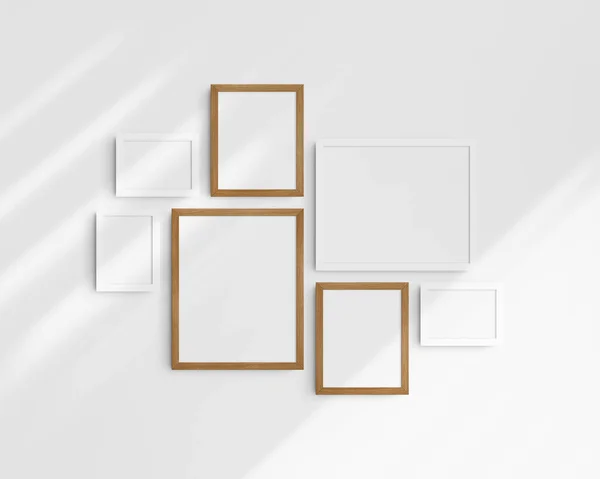 画廊壁面造型 7个白色和樱桃木框架 简约的框架模型 3个水平框架和4个垂直框架 5X7 7X5 8X10 12X15 15X12 白色墙壁上有阴影 图库图片