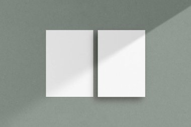 İki beyaz dikey kağıt maketi, A4 / A5 / A6 el ilanı modeli, kağıt, mektup, davetiye kartı, yeşil arka planda gölgeli.