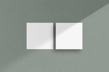 İki tane beyaz kare kağıt maketi, el ilanı maketi, kare kağıt kağıtlar, davetiye kartları, gölgeli yeşil bir arka plan..