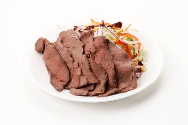 İnce dilimlenmiş soğuk biftek ve beyaz tabakta sebze salatası..