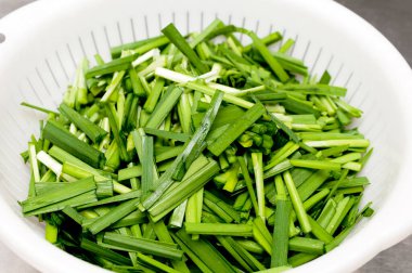 Chopped garlic chives in White plastic colander