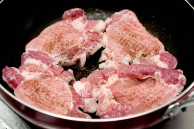Kızartma tavasında domuz eti pişiriyorum. 