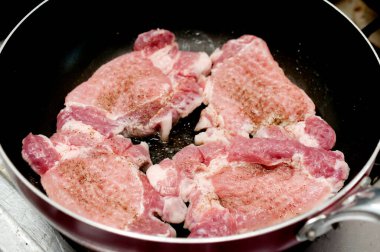 Kızartma tavasında domuz eti pişiriyorum. 