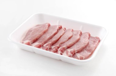 Beyaz arka planda köpük tepsisinin içinde domuz eti.