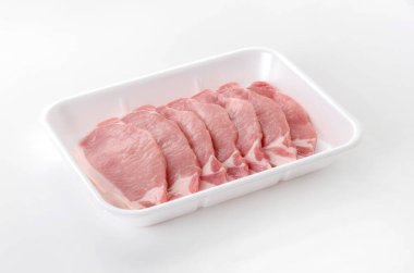 Beyaz arka planda köpük tepsisinin içinde domuz eti.