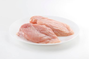 Beyaz arka planda bir tabakta çiğ tavuk göğsü