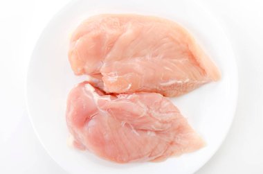 Beyaz arka planda bir tabakta çiğ tavuk göğsü