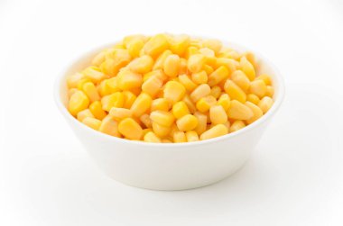 Beyaz arka planda beyaz bir kasede konserve mısır.