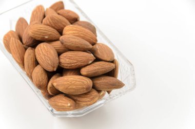 Beyaz arka planda küçük bir cam kasede jöleli badem.