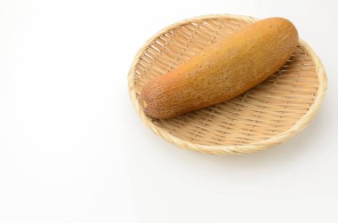 Moui, beyaz arka planda bambu kevgire bulanmış sarı salatalık.