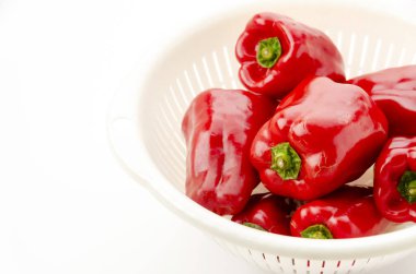 Beyaz arka planda beyaz plastik kevgir ile taze kırmızı dolma biber.