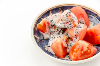 Beyaz arka planda küçük bir tabakta siyah susamlı mayonez salatası..