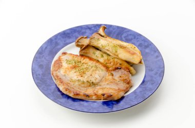 Beyaz arka planda Eryngii mantarlı sahanda domuz filetosu.