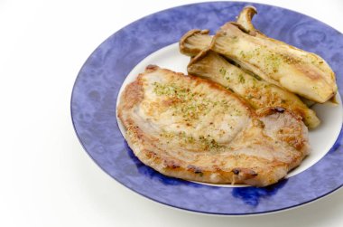 Beyaz arka planda Eryngii mantarlı sahanda domuz filetosu.