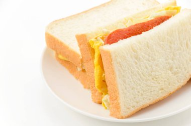 Domuz eti, tamagoyaki (Japon omleti) ve lahana salatası dilimlenmiş ekmek dilimleri arasında.