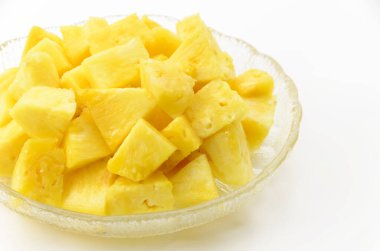 Beyaz arka planda şeffaf cam bir çanakta ananas parçaları.