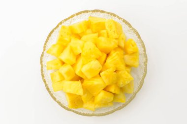 Beyaz arka planda şeffaf cam bir çanakta ananas parçaları.
