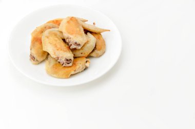 Beyaz tabakta tuzlanmış tavuk kanadı.