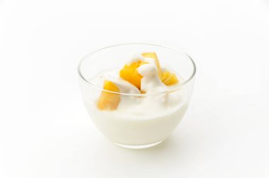 Beyaz arka planda ananas parçaları olan şeffaf cam yoğurt kasesi.