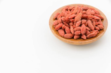 Dried goji berries on a wooden plate on white background clipart