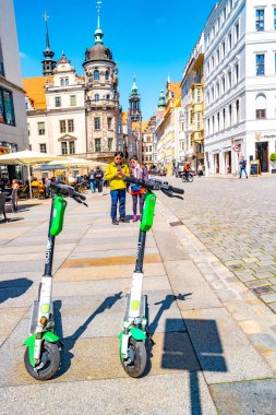 Dresden, Almanya - 3 Mayıs 2023: Tarihi şehir merkezi, Castle Caddesi 'nde elektrikli scooterlar, kafeler, dükkanlar ve insanlar. Modern ve enerjik görün Dresden. Şehir merkezinin güneşli bir günde ve mavi gökyüzünde.