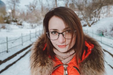 Turuncu ceketli mutlu bir kadının portresi. Kış mevsiminde şehir parkında bir eşarpla..