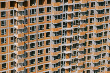 Tamamlanmamış konut binası. Gündüz vakti inşaat alanında beton bina. Beton çerçeve ve tuğla duvarlar. Ön cephe yakın plan. Yapı deseni.
