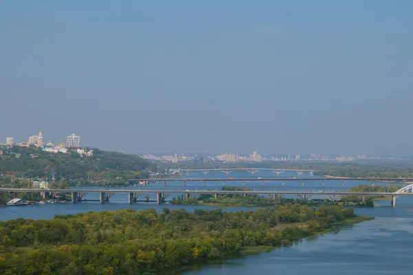 緑の木々に覆われた島と川の空中ビュー 前景と背景に都市地区と川を渡るいくつかの橋 — ストック写真