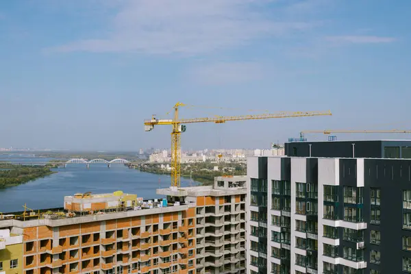 Binanın en üst katında. Tamamlanmamış konut binası. İnşaat alanı ve gündüz inşaatı. Mavi nehre karşı inşaat alanı. Beton çerçeve ve tuğla duvarlar. Ön cephe yakın plan. 