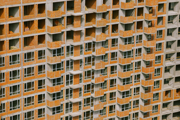 Unfinished residential building. Concrete building at a construction site in the day time. Concrete frame and brick walls. Facade close-up. Construction pattern.