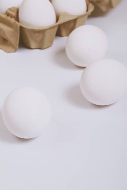 Beyaz yumurtalar parlak arka planda ve kahverengi yumurta tepsisinde. Seçici odaklanma. Kavram sahnesi.